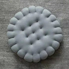 Graues, rundes, gepolstertes Sitzkissen auf grauem Teppich, modernes Design, Wohnzimmer-Dekor.