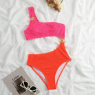Neonfarbener Bikini mit asymmetrischem Design, goldenen Ringen, auf weißem Hintergrund.