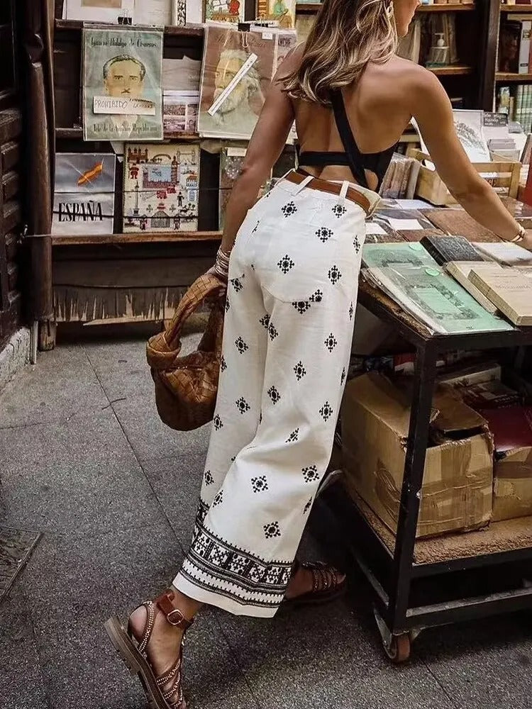 Frau in modischem Sommeroutfit mit weißem, besticktem Rock und schwarzem Top, stöbert in einem Buchladen. Perfekt für Boho-Mode und Sommertrends.