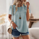 Damenmode: Luftige, hellblaue Bluse mit Spitzenmuster, kombiniert mit Jeansshorts. Perfekt für Sommer-Outfits und Freizeit-Looks.