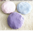 Drei runde Kissen in Pastellfarben, lila, rosa, blau, auf weißem Teppich, Dekokissen Wohnzimmer.