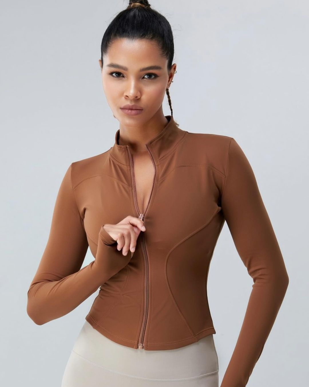 Frau in brauner Sportjacke mit Reißverschluss, modisch und funktional. Perfekt für Fitness, Yoga und Freizeit. Hochwertige Sportbekleidung.