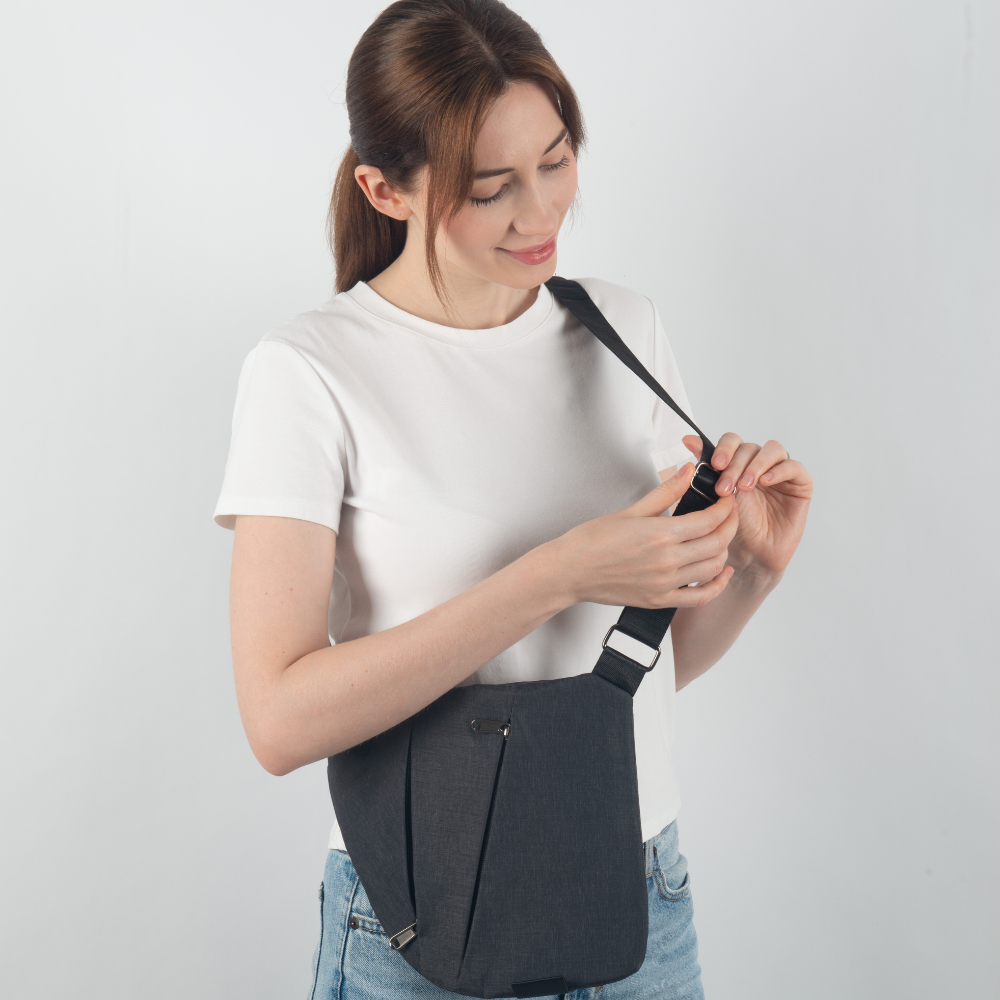 Frau mit schwarzer Umhängetasche, weißem T-Shirt und blauer Jeans, modisches Accessoire.