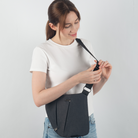 Frau mit schwarzer Umhängetasche, weißem T-Shirt und blauer Jeans, modisches Accessoire.