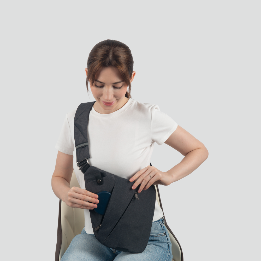 Frau mit schwarzer Umhängetasche, weißem T-Shirt und blauer Jeans, Smartphone in der Hand.