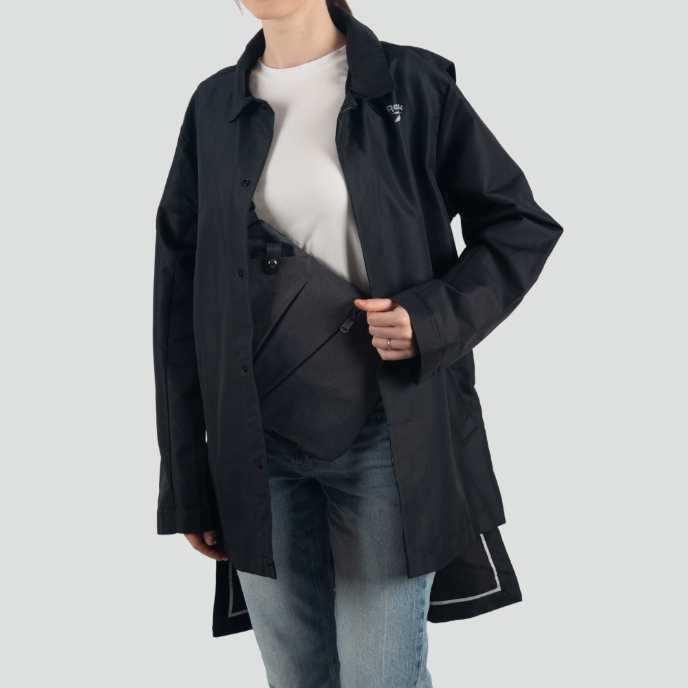 Frau in schwarzem Mantel mit grauer Umhängetasche, lässige Mode, Jeans, weißes T-Shirt.