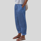 Frau in blauer Leinenhose, gestreiftem Oberteil und Sandalen, lässige Sommermode.