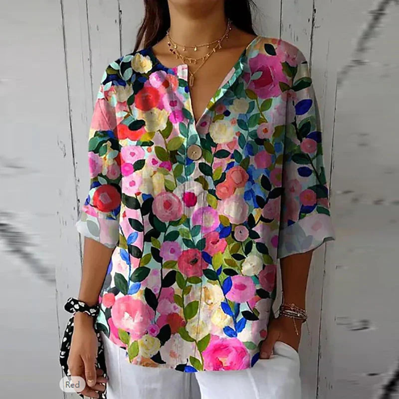 Frau in bunter, floraler Langarmbluse, lässig, elegant, Vintage-Stil, vor weißem Hintergrund.