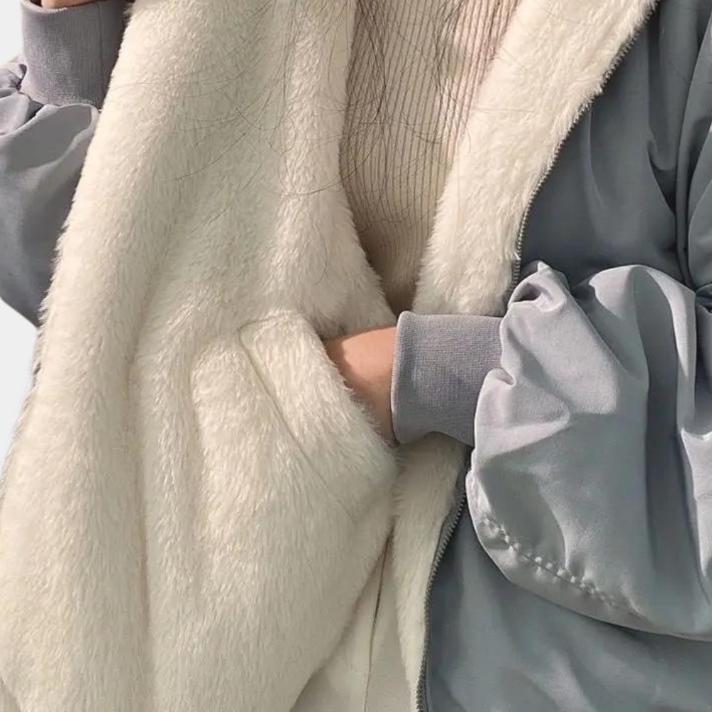 Damen-Winterjacke mit weichem, weißem Kunstfellfutter und grauer Außenschicht. Stilvoll, warm und perfekt für kalte Wintertage.