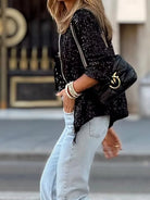 Damenmode 2024: Schwarze Paillettenjacke mit langen Ärmeln, kombiniert mit hellen Jeans. Elegante Frühlings- und Sommerbekleidung für Frauen.