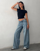 Frau in schwarzem Top und weiten, vintage-blauen Jeans, modisch, lässig, Streetwear.