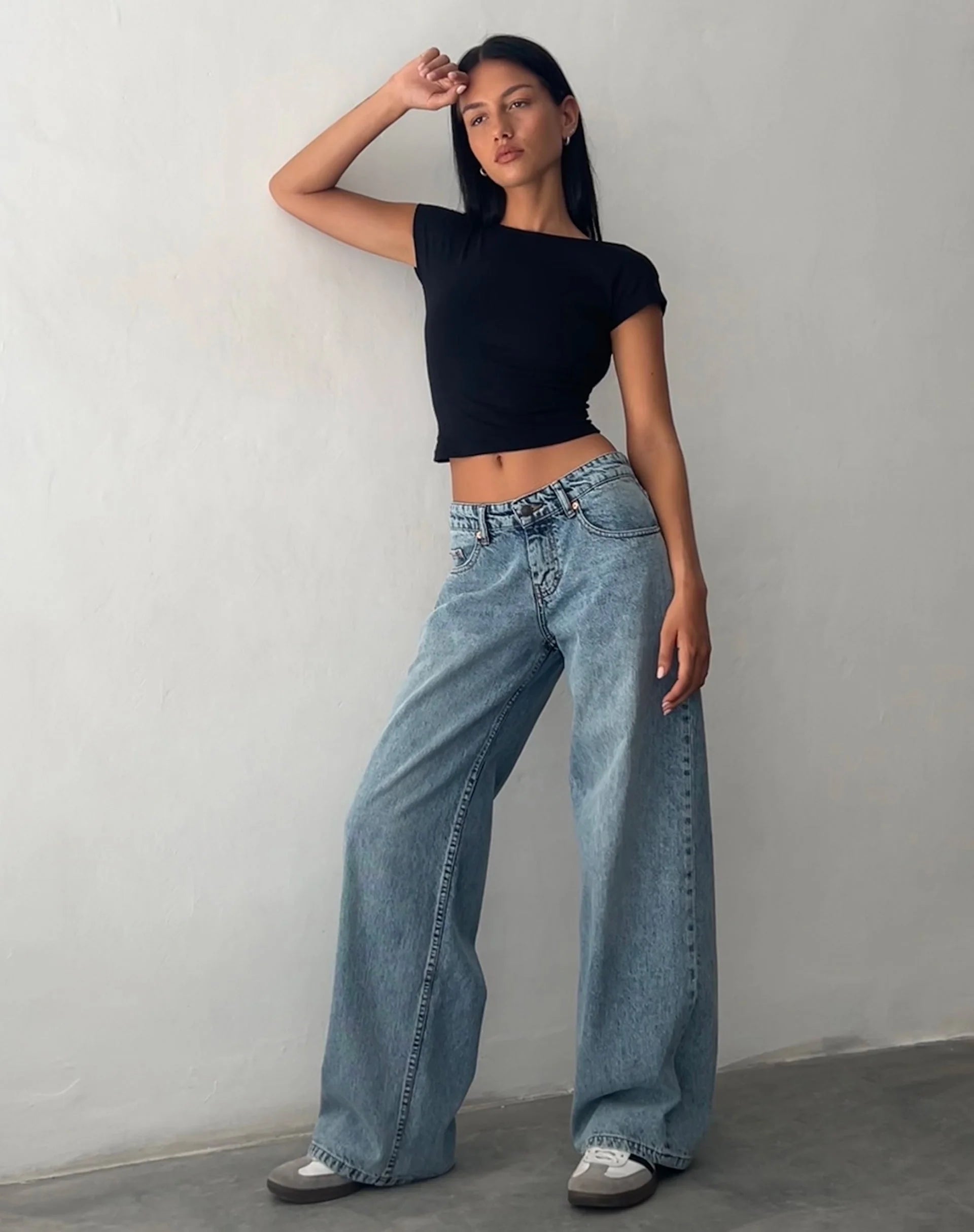 Frau in schwarzem Top und weiten, vintage-blauen Jeans, modisch, lässig, Streetwear.