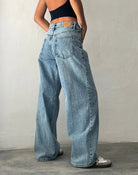 Frau in schwarzem Top und weiten, vintage-blauen Jeans aus Lycra, seitliche Ansicht.