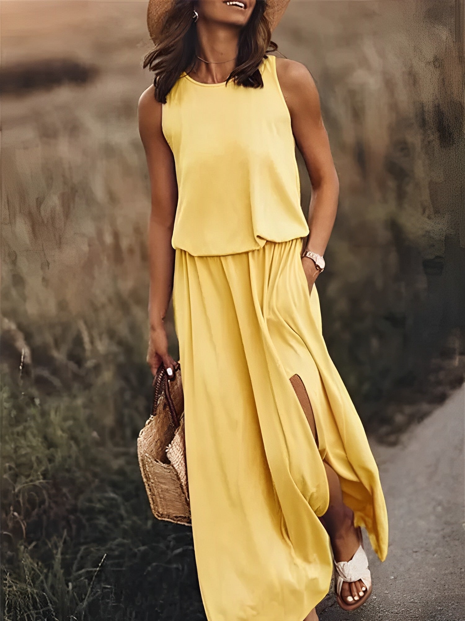 Frau in gelbem ärmellosen Sommerkleid, Strohhut, Sandalen, mit Strohtasche auf Wiese.