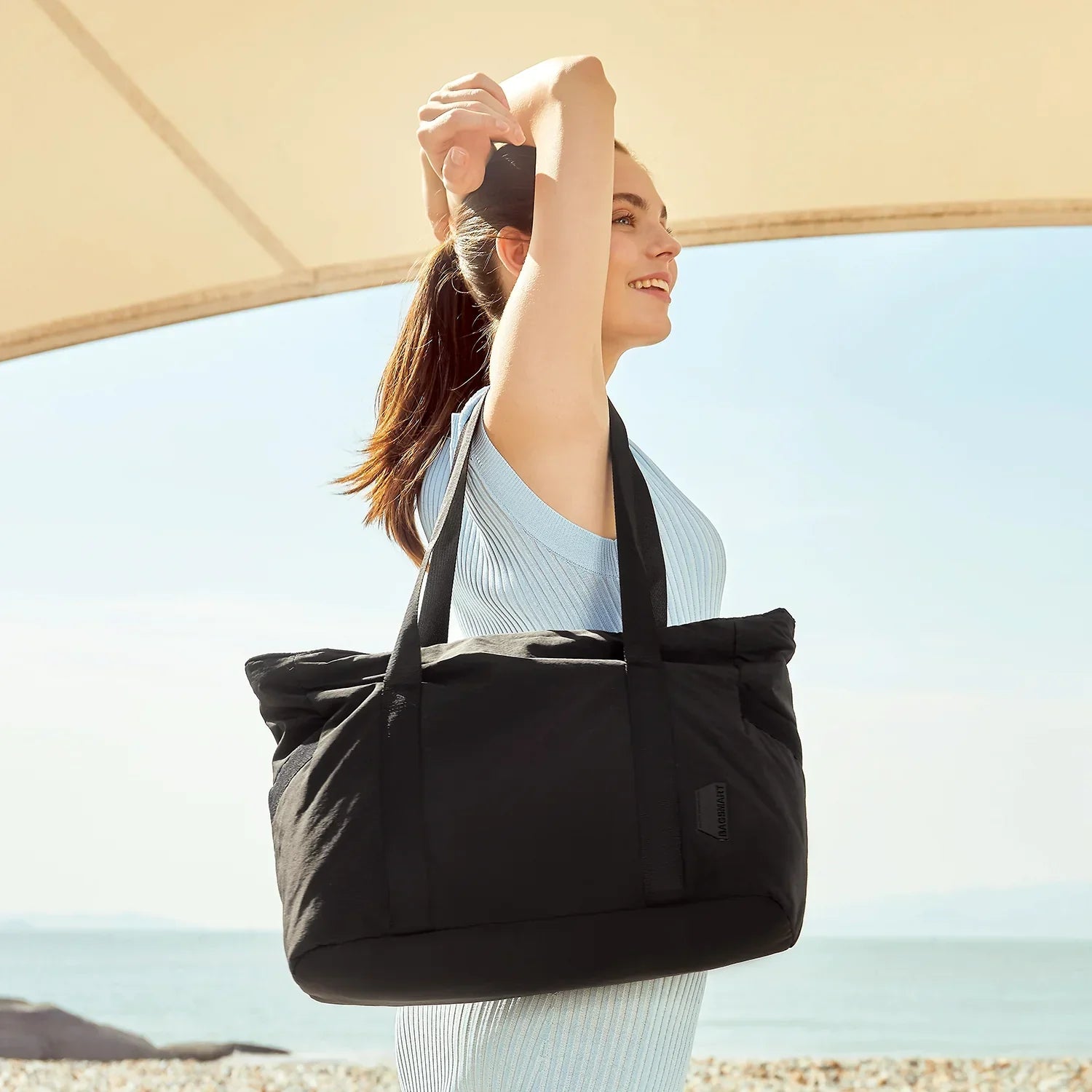 Frau mit schwarzer Tragetasche, Sommerkleid, Strandhintergrund, Modeaccessoire, Freizeitlook.