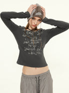 Damenmode: Graues Langarmshirt mit abstraktem Print, kombiniert mit grauer Hose und Mütze. Trendige Freizeitkleidung für Herbst/Winter.