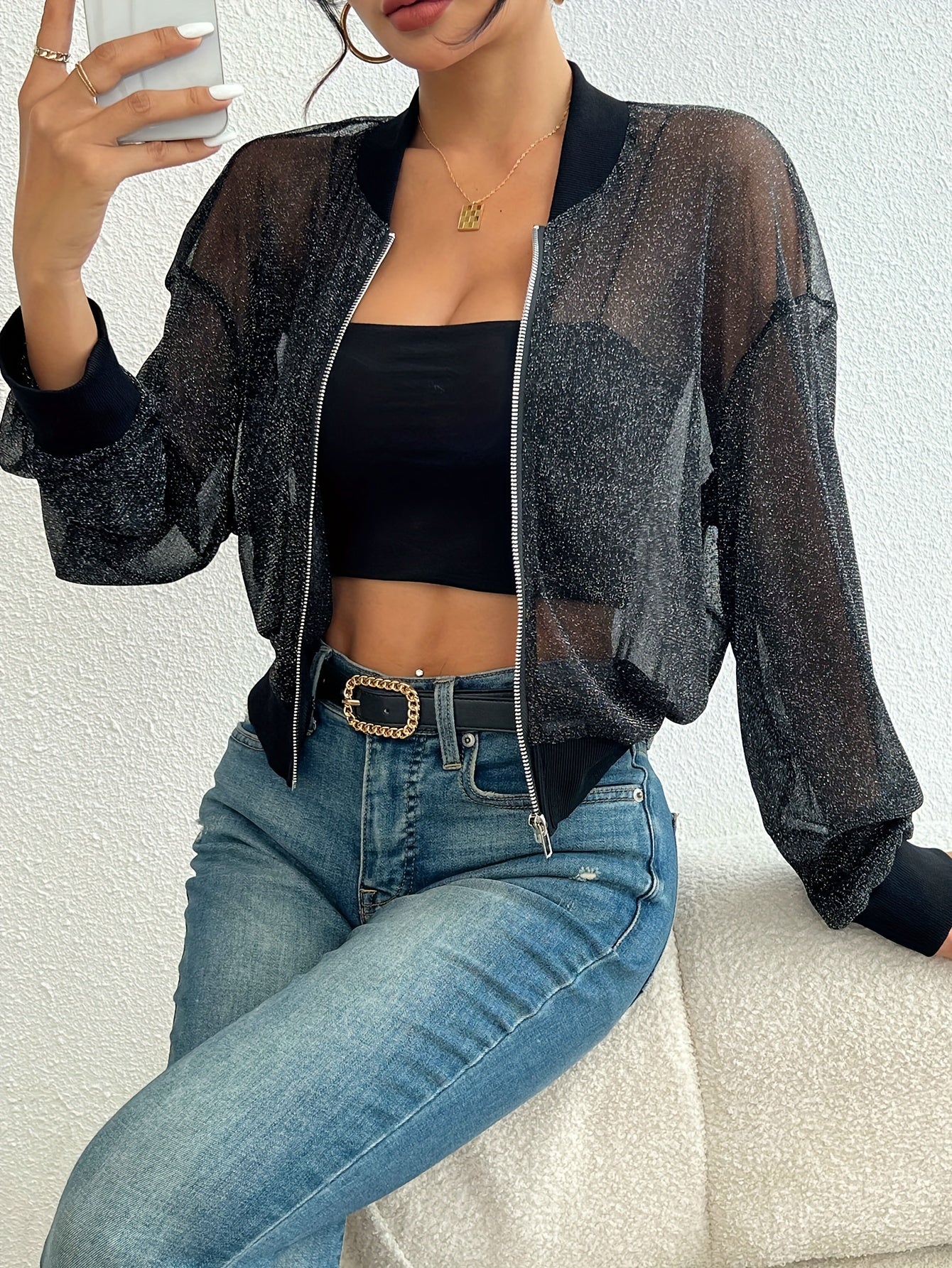 Damenmode: Transparente schwarze Glitzerjacke, kombiniert mit schwarzem Top und blauer Jeans. Trendige Freizeitkleidung für stilvolle Outfits.
