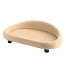 Beiges Katzenbett aus Plüsch, oval, mit erhöhtem Rand und schwarzen Beinen, gemütlich und modern.