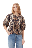 Frau in modischer Leopardenbluse mit Puffärmeln und blauer Jeans. Trendige Damenmode, Animal-Print, lässiger Look.
