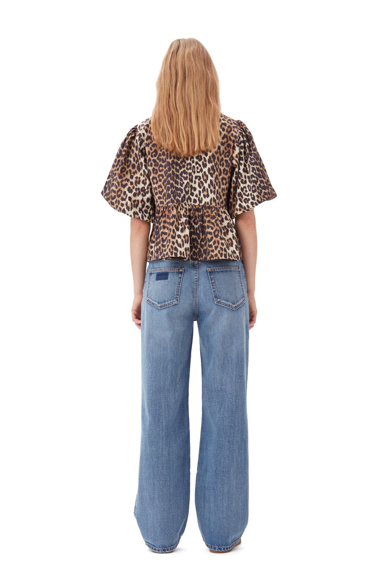 Frau in Leopardenbluse und weiten Jeans, Rückansicht. Modetrend, Damenmode, lässiger Stil, Tiermuster, Denim, Streetwear, Fashion 2023.