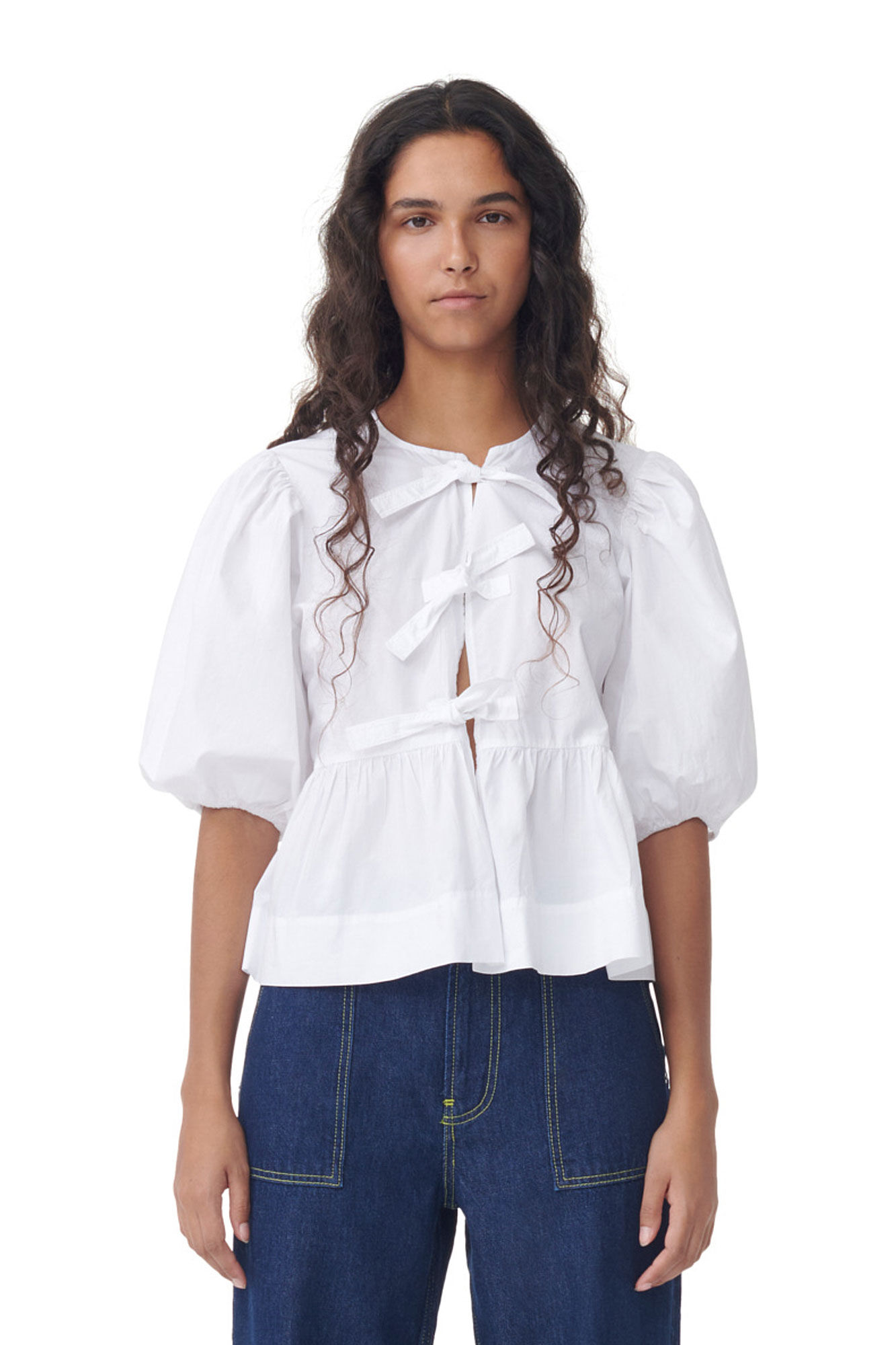 Weiße Bluse mit Puffärmeln und Schleifen, kombiniert mit dunkelblauer Jeans. Modetrend, Damenbekleidung, eleganter Look, Freizeitstil.