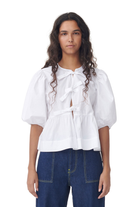 Weiße Bluse mit Puffärmeln und Schleifen, kombiniert mit dunkelblauer Jeans. Modetrend, Damenbekleidung, eleganter Look, Freizeitstil.