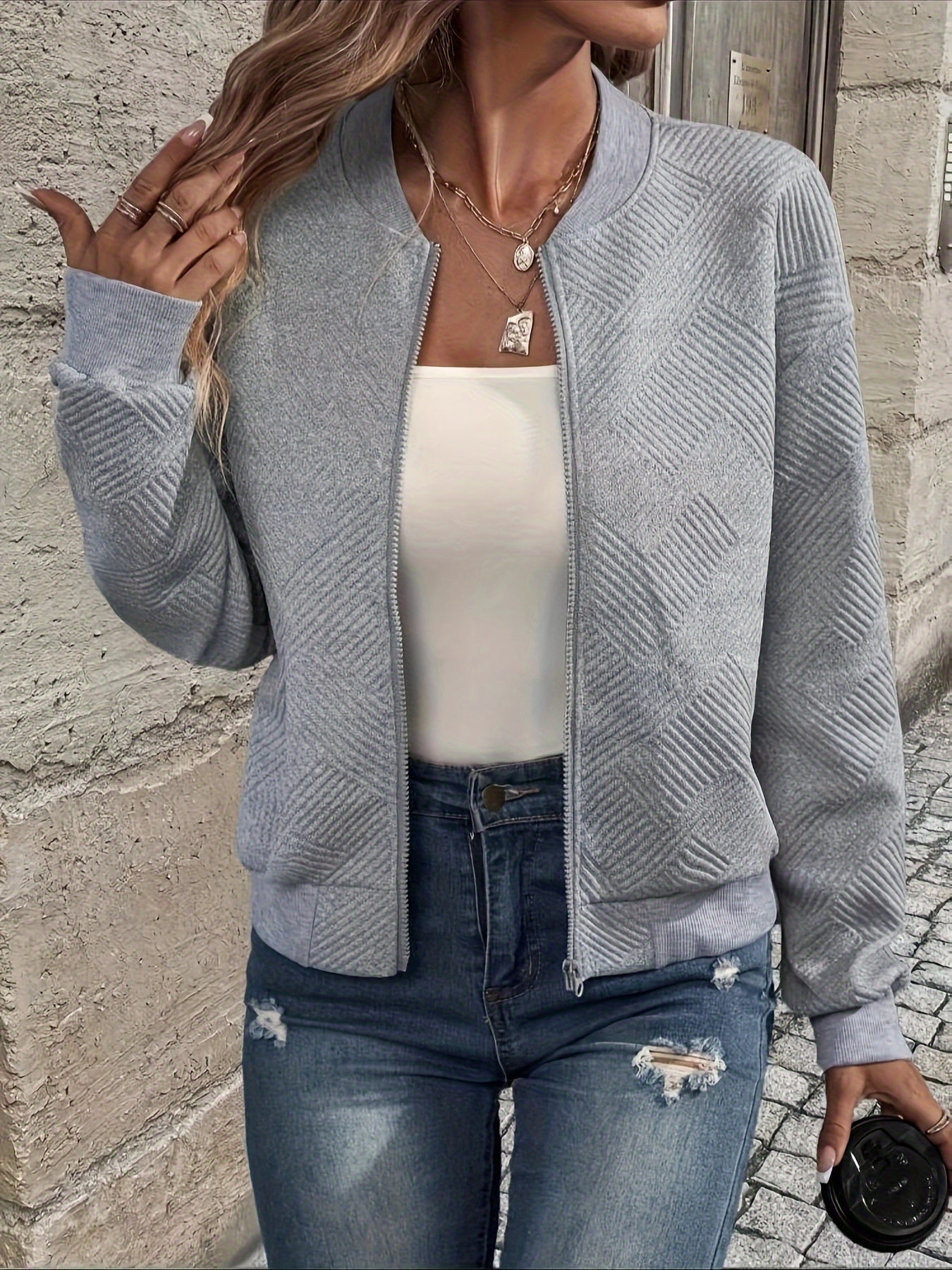 Damenmode: Graue Strickjacke mit Reißverschluss, kombiniert mit weißem Top und Jeans. Trendige Freizeitkleidung für stilvolle Outfits.