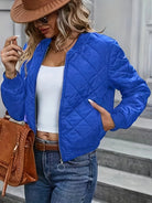 Frau in blauer Steppjacke, weißem Top und Jeans, trägt braune Tasche und Hut. Modetrends, Damenbekleidung, Herbstmode, Streetstyle.