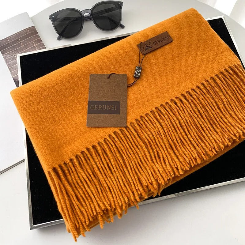 Luxuriöser orangefarbener Schal aus Kaschmir mit Fransen, stilvoll präsentiert in einer Geschenkbox. Perfekt für elegante Herbst- und Wintermode.