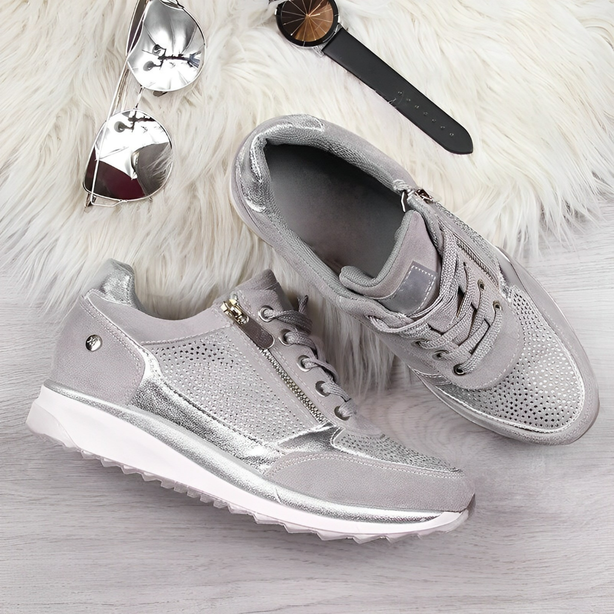 Damen Sneaker in Silber mit Glitzer, Reißverschluss und Schnürung auf hellem Holzuntergrund. Modische Schuhe, ideal für trendige Outfits.