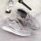 Damen Sneaker in Silber mit Glitzer, Reißverschluss und Schnürung auf hellem Holzuntergrund. Modische Schuhe, ideal für trendige Outfits.