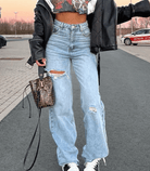 Blaue zerrissene Baggy-Jeans für Damen, lässiger Streetwear-Stil, ideal für trendige Outfits. Perfekt kombiniert mit Lederjacke und Sneakers.