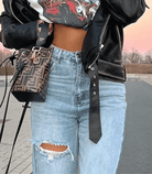 Blaue zerrissene Baggy-Jeans, kombiniert mit schwarzer Lederjacke und Designer-Handtasche. Trendige Streetwear für Damen.