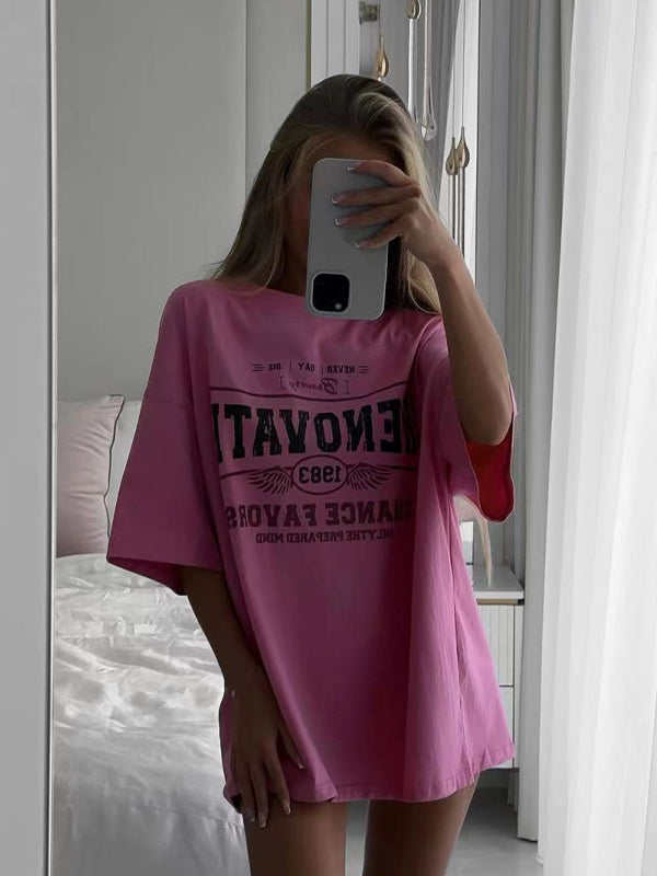 Frau in rosa Oversize-T-Shirt mit Smartphone vor Spiegel. Trendige Mode, lässiger Look, Selfie, modernes Design, bequeme Kleidung.