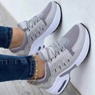 Graue Damen-Sneaker mit weißer Sohle, atmungsaktivem Mesh-Obermaterial und modischem Design. Perfekt für Sport und Freizeit.