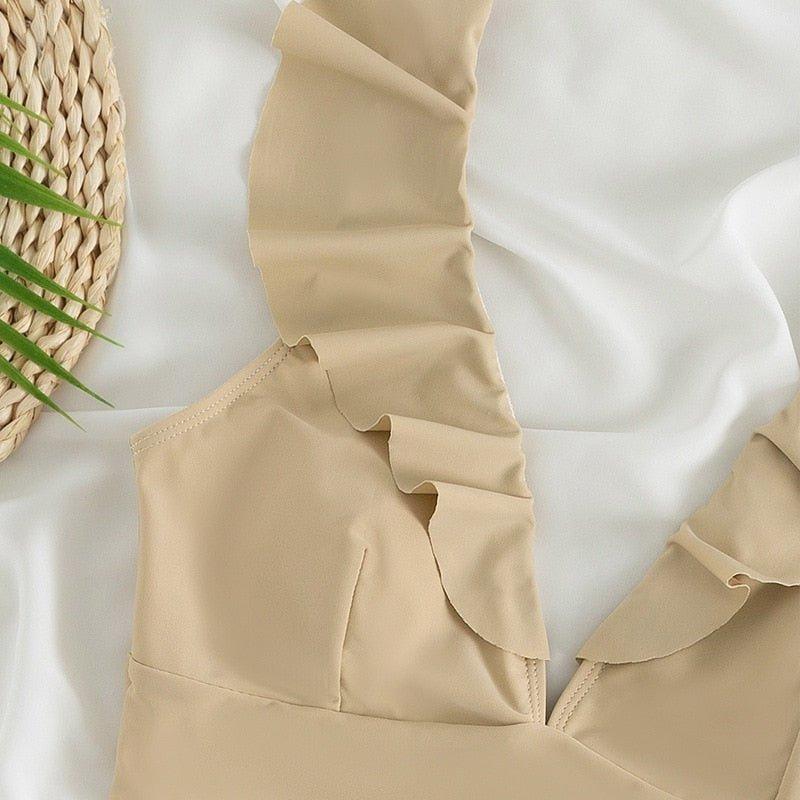 Beiger Rüschen-Bikini auf weißem Hintergrund, ideal für Sommermode. Perfekt für Strandurlaub und stilvolle Bademode. Hochwertige Materialien.