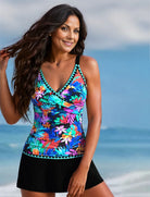 Frau im bunten Tankini mit Blumenmuster am Strand, lächelnd. Sommermode, Bademode, Strandkleidung, tropisches Design, Damenmode.