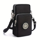 Schwarze Umhängetasche mit zwei Reißverschlussfächern, verstellbarem Gurt und stylischem Logo-Emblem. Perfekt für Damenmode und Accessoires.