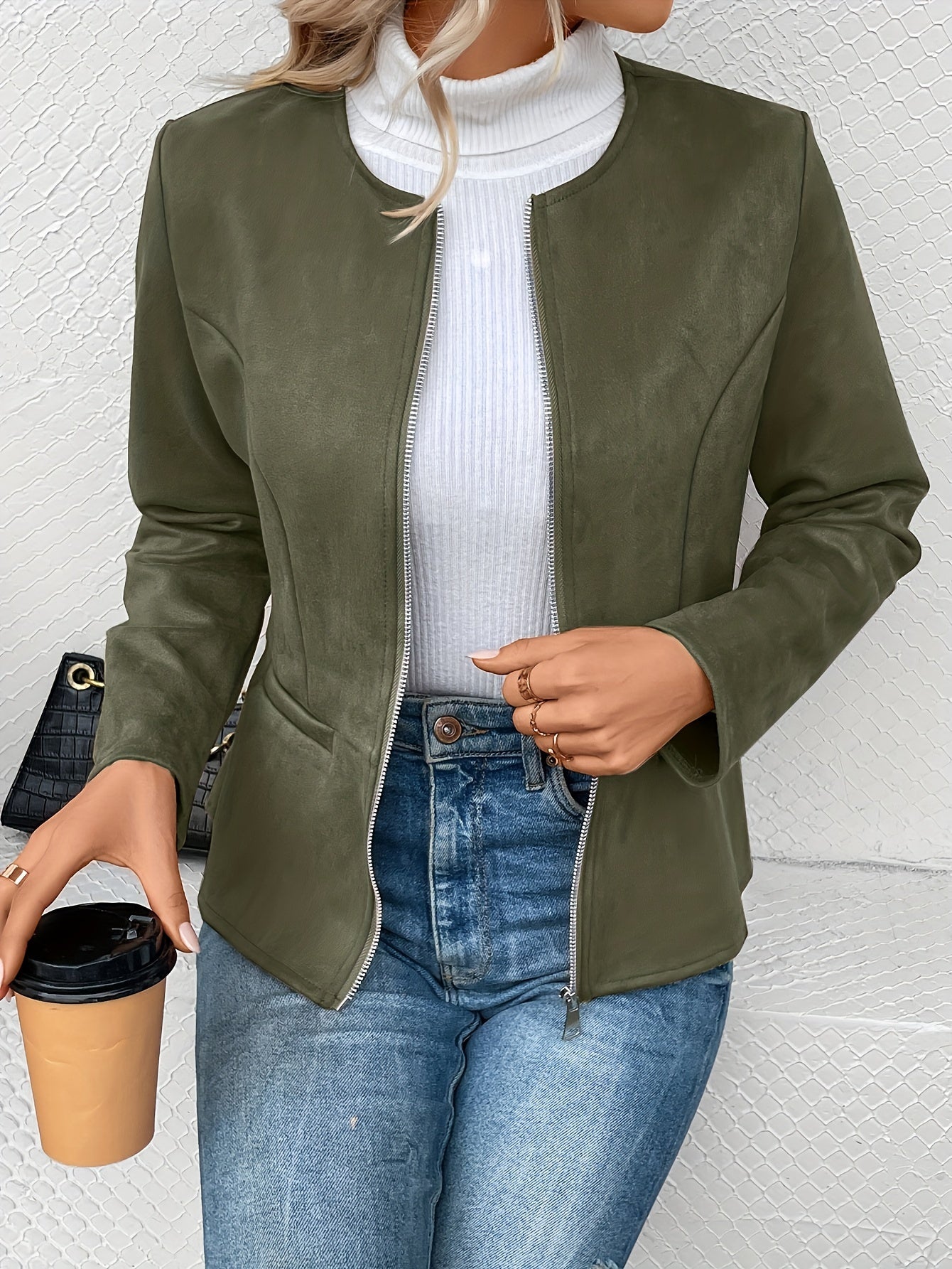 Damenjacke in Olivgrün, kombiniert mit weißem Rollkragenpullover und blauer Jeans. Modetrend, stilvolle Herbstbekleidung, lässiger Look.