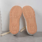 Beige Sneaker-Sohlen mit rutschfestem Profil auf grauem Hintergrund. Ideal für Mode, Komfort und Alltag. Hochwertige Turnschuhe für Damen und Herren.