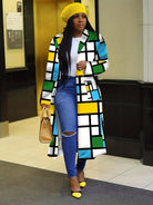 Frau in modernem, farbenfrohem Mantel mit geometrischem Muster, gelber Mütze und Pumps. Modetrend, Streetstyle, Herbstmode, Damenbekleidung.