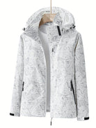 Weiße Damenjacke mit Kapuze, tropischem Blattmuster und Reißverschlusstaschen. Perfekt für Outdoor-Aktivitäten. Modisch, funktional, wasserabweisend.