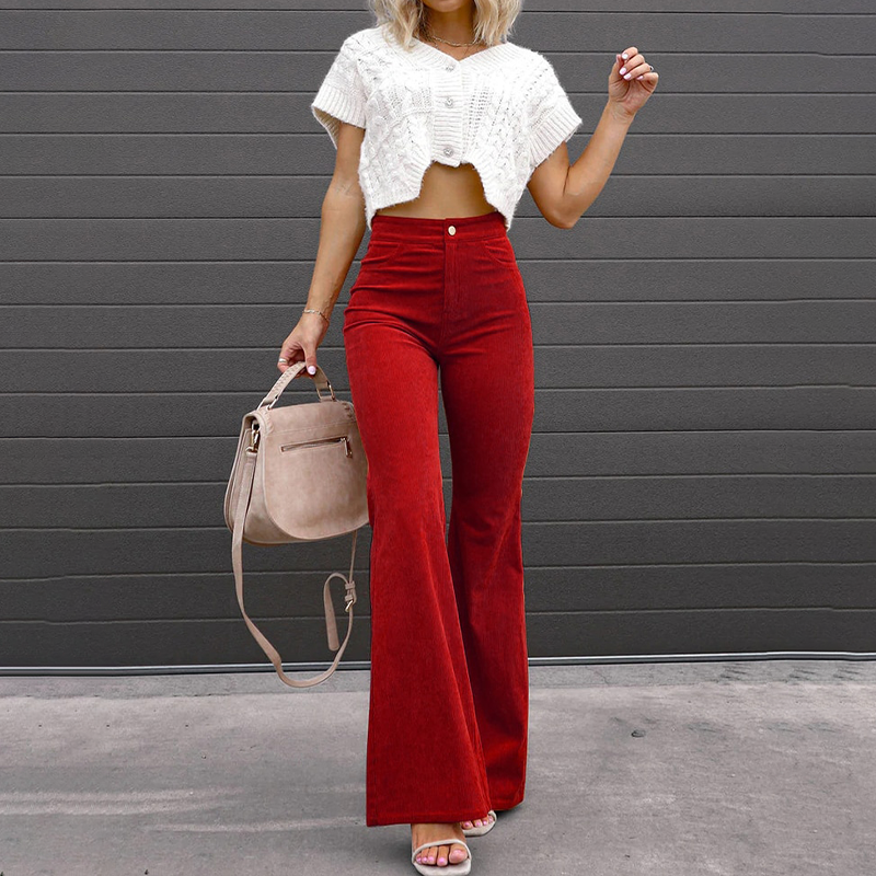 Frau in roter Schlaghose und weißem Strickoberteil, hält eine beige Handtasche. Modetrend, Damenmode, stilvolle Outfits, Herbstmode.