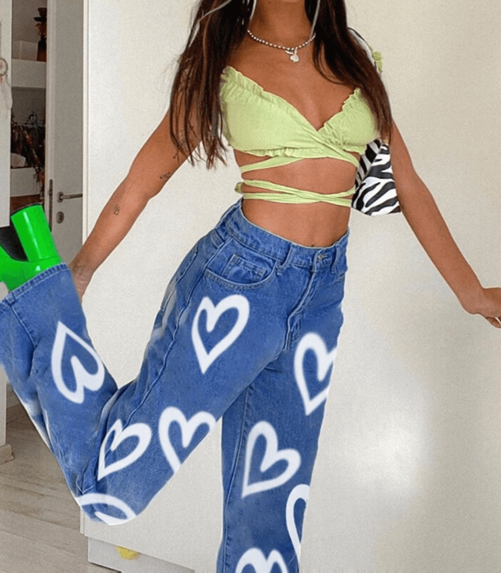Damen-Jeans mit Herz-Print, kombiniert mit grünem Crop-Top. Trendige Mode, lässiger Stil, ideal für Sommer-Outfits und Streetwear.