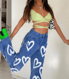 Damen-Jeans mit Herz-Print, kombiniert mit grünem Crop-Top. Trendige Mode, ideal für Sommer-Outfits. Jetzt entdecken bei Amodafashion.