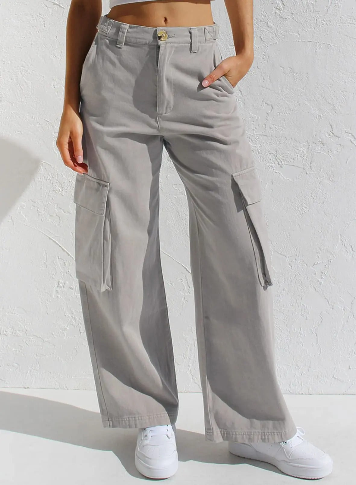 Graue Cargo-Hose für Damen mit weitem Bein und Seitentaschen, kombiniert mit weißen Sneakern. Perfekt für lässige und modische Outfits.