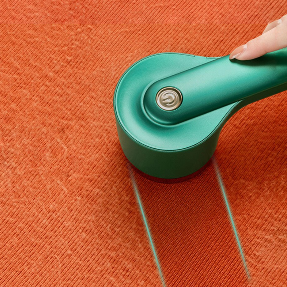 Grüner Fusselentferner auf orangefarbenem Stoff, entfernt effektiv Fusseln und Flusen. Ideal für Kleidungspflege und Textilreinigung.