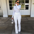 Elegante Frau in weißem Outfit: Langarmshirt, Schlaghose, Sonnenbrille. Perfekt für modische Streetwear und stilvolle Freizeitlooks.