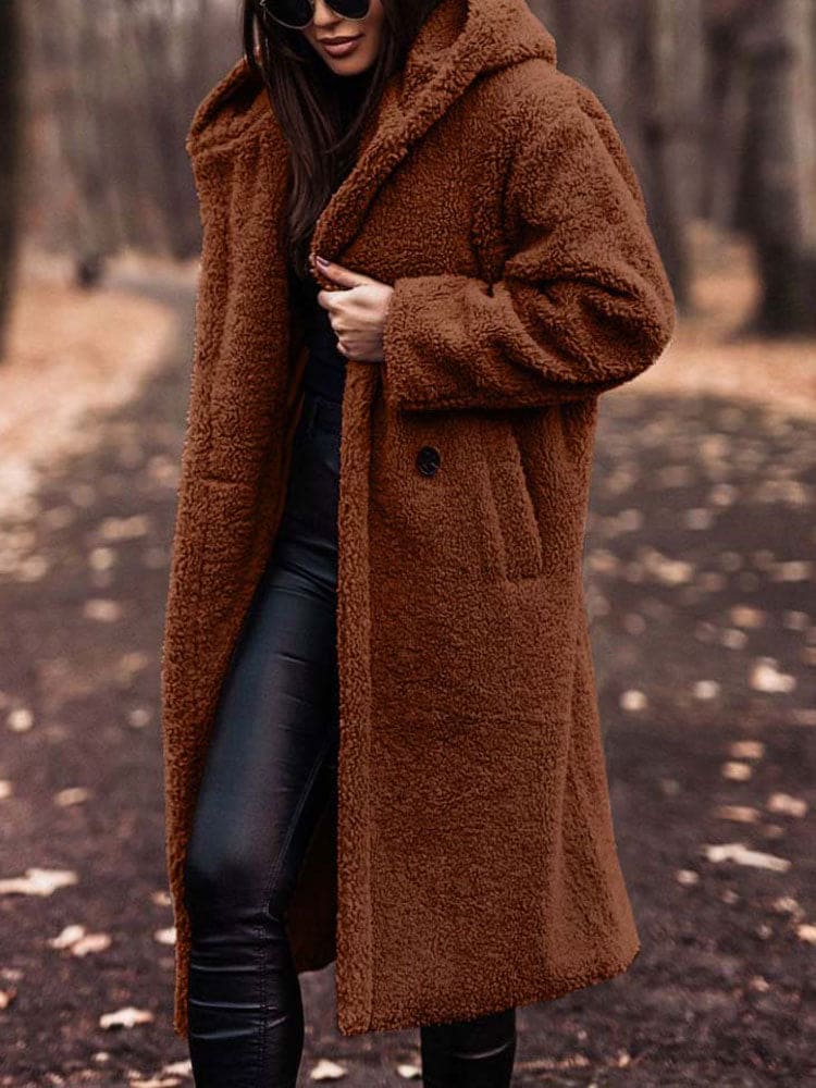 Frau im braunen Teddy-Mantel im Herbstwald. Modetrend, kuscheliger Wintermantel, stilvolle Damenbekleidung, warme Oberbekleidung.