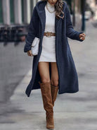 Frau in elegantem, blauem Teddy-Mantel, weißem Strickkleid und braunen Stiefeln. Modetrend Herbst/Winter, stilvoller Streetstyle-Look.